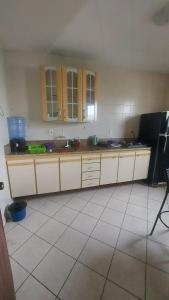 cocina con armarios blancos y suelo de baldosa en Apartamento 2 Quartos Praia do Morro, en Guarapari