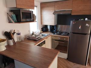 a kitchen with a stainless steel refrigerator and wooden cabinets at Camping Quiberon Mobilhomes bord de mer Conguel in Quiberon