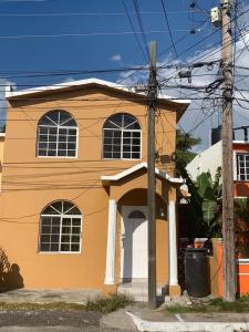 a orange and white house on a street at BridgeView Arcadia One in Portmore