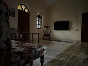 a living room with a tv and a chair at Casa Amarela in Cuncolim