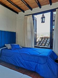 1 cama azul en un dormitorio con ventana grande en Hostal Oycate, en Oicatá
