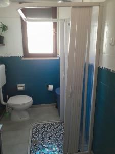 Baño azul con aseo y ventana en Appartamento a Ravenna - 100 metri dalla spiaggia en Lido Adriano