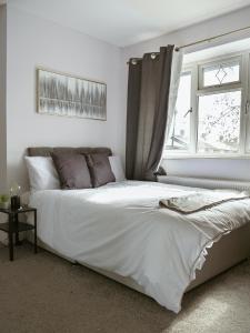 a bedroom with a white bed with a window at Urban Oasis in Abbey Wood