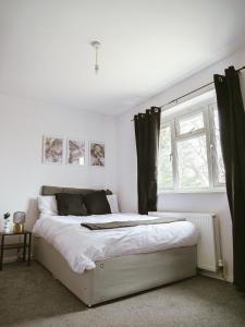 a bedroom with a white bed with black curtains at Urban Oasis in Abbey Wood