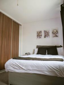 a bedroom with a large bed with white sheets at Urban Oasis in Abbey Wood
