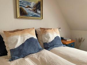 a bed with two pillows and a painting on the wall at Nygaard B&B in Nørre Nebel