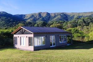 a small house in a field with mountains in the background at Conectate con la Naturaleza in Salta