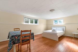 a bedroom with a bed and a table and two windows at Tranquil Haven near Attractions: 4 BD Suite in Vancouver