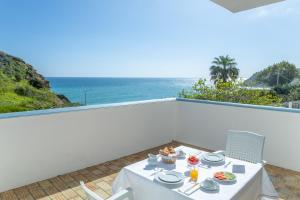 una mesa con comida en un balcón con vistas al océano en MC Suites Burgau with amazing front sea view, en Burgau