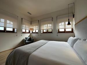 a bedroom with a large white bed and windows at Hotel El Rosal de Cudillero in Cudillero