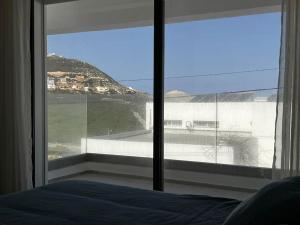 sypialnia z dużym oknem z widokiem na budynek w obiekcie Duplex Blue Lagoon w mieście Bizerta