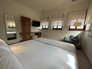 a bedroom with a bed and a chair and windows at Hotel El Rosal de Cudillero in Cudillero