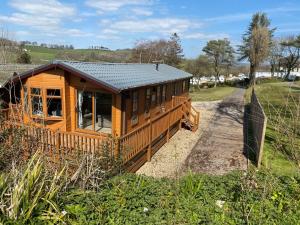 a wooden cabin in a field with a fence at Newlands Holidays in Bridport