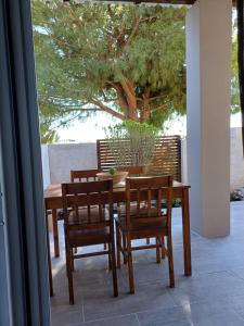 drewniany stół i krzesła na patio z drzewem w obiekcie Abelaki Holiday Home w mieście Paramonas