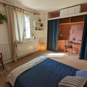 a bedroom with a blue bed and a desk at Ecolodge La Belle Verte in Saint-Mʼhervé