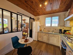 a kitchen with a table and a white refrigerator at Le Beau Repère in Beaurepaire