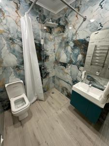 a bathroom with a toilet and a sink at Lux Plaza Hotel in Arbatʼ