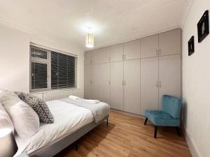 a bedroom with a bed and a blue chair at Charming 3-bedroom family home in London