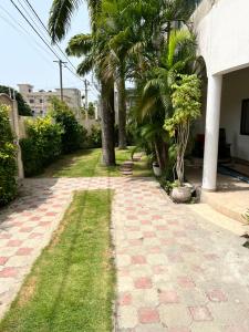 a walkway with palm trees and grass next to a building at VillaXXL & Pool, Fidjrosse, route des pêches, Cotonou in Godomè