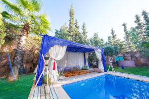 een blauwe luifel boven een zwembad met een tent bij Villa Timskrine - Panoramic Mountains View in Marrakesh