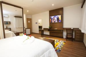 a hotel room with a bed and a flat screen tv at São Carlos Marklin Suítes in São Carlos