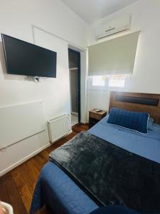 1 dormitorio con 1 cama azul y TV de pantalla plana en Maktub Europa - Hostal Boutique, en Santiago