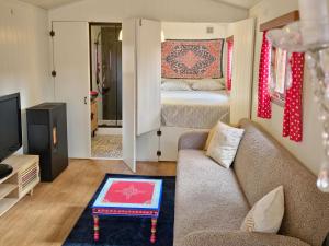 een woonkamer met een bank en een bed bij pipowagen met prive Hot tub in Lanaken
