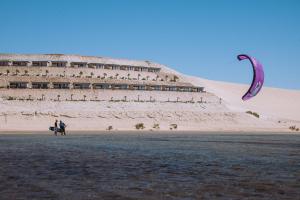 達赫拉的住宿－PARAISO DAKHLA，风筝在建筑物前飞行的人