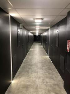 un couloir aux murs noirs et un long couloir avec des stands dans l'établissement Apartimento Hydral Fresco, à Wrocław