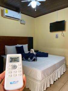 a person holding a remote control in front of a bed at Hospedaje Coffee and cocktails in Estelí