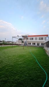 un gran edificio con un campo de fútbol delante en Hotel Shri kishori farm, en Mathura