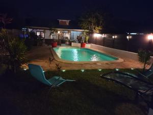 a swimming pool in a yard at night at Hudace maison partagée in Saint-Laurent du Maroni