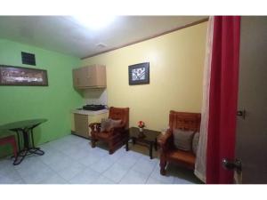 a living room with two chairs and a table and a kitchen at OYO 1048 Jomckayl Apartelle in Naga