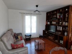 uma sala de estar com um sofá e uma televisão em Maison de Lili em Florensac