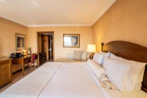 a large white bed in a room with a desk at Likoria Hotel in Arachova