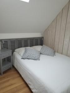 a bedroom with a white bed with two pillows at La Forge, gîte familial,à Sainte Mère Eglise in Sainte-Mère-Église