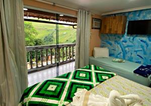 1 dormitorio con 2 camas y balcón con vistas. en Pousada Amigos do Caetés en Angra dos Reis