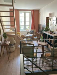 ein Wohnzimmer mit einer Treppe und ein Wohnzimmer mit Tischen in der Unterkunft La Maison d’Aromarie in Tournus