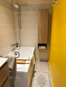 ein kleines Bad mit einer Badewanne und einem Waschbecken in der Unterkunft La Maison d’Aromarie in Tournus