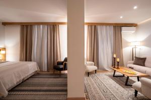 Likoria Hotel في أراخوفا: غرفه فندقيه بسرير واريكه وطاولة