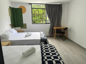 a room with two beds and a desk and a window at Hostal Pajuil in Armenia +17 photos