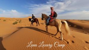 two people riding horses in the desert at Luna luxury camp in Merzouga