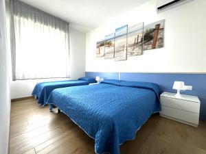 una camera con un letto blu e una finestra di Villaggio Azzurro Plus a Bibione