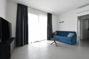 ein Wohnzimmer mit einem blauen Sofa und einem TV in der Unterkunft Les Jolie Apartament in Lido di Jesolo