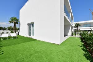 ein weißes Haus mit grünem Rasen in der Unterkunft Les Jolie Apartament in Lido di Jesolo