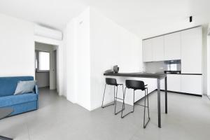 eine Küche mit einem Tisch und Stühlen sowie einem blauen Sofa in der Unterkunft Les Jolie Apartament in Lido di Jesolo