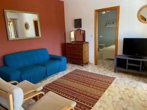 ein Wohnzimmer mit einem blauen Sofa und einem TV in der Unterkunft Vista Xalo in Alcalalí