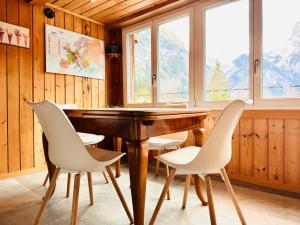 a dining room with a wooden table and white chairs at Cozy Apartment in Vintage House in Kandersteg in Kandersteg