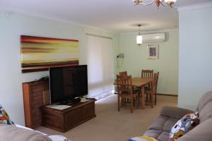 a living room with a flat screen tv and a table at Comfort and Convenient in Perth