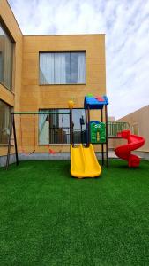 a playground with a slide and a swing at Al-Mona Resort شاليه المنى الخبر in Al Khobar